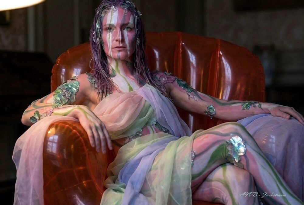 Autoportrait photographique d'Artemis Irenäus von Baste, 'Arty', en costume d'art vivant avec body painting floral, assise dans son fauteuil gonflable orange à Coire (Chur), Suisse, pour l'exposition Néo-Folklorisme Contemporain.