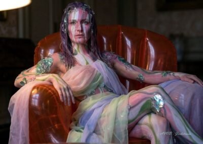 Autoportrait photographique d'Artemis Irenäus von Baste, 'Arty', en costume d'art vivant avec body painting floral, assise dans son fauteuil gonflable orange à Coire (Chur), Suisse, pour l'exposition Néo-Folklorisme Contemporain.