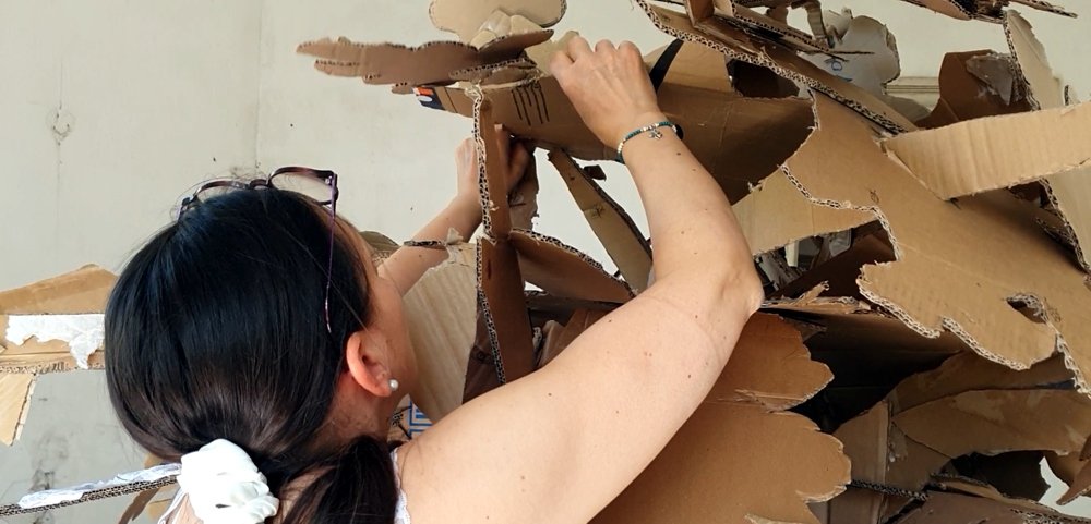L'artiste Isabelle Morin assemblant son arbre en carton brut dans un salon en ruine au château du Bois-la-Croix